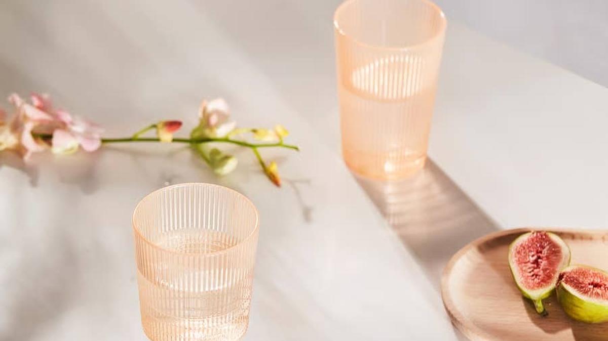 Two plastic orange glasses on a table with friut.