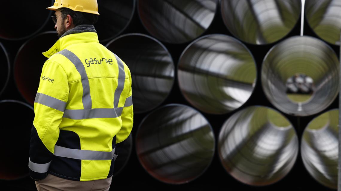 A worker stands near some natural gas pipeline parts in this file photo. West Coast leaders are calling on the federal government to reconsider plans to expand a fracked gas pipeline throughout western states.