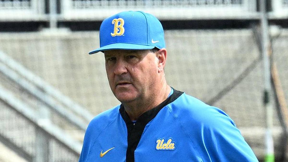  Jun 17, 2025; Omaha, Neb, USA; UCLA Bruins head coach John Savage (22) walks to the dugout before the restart of the game against the LSU Tigers at Charles Schwab Field. Mandatory Credit: Steven Branscombe-Imagn Images | Steven Branscombe-Imagn Images 
