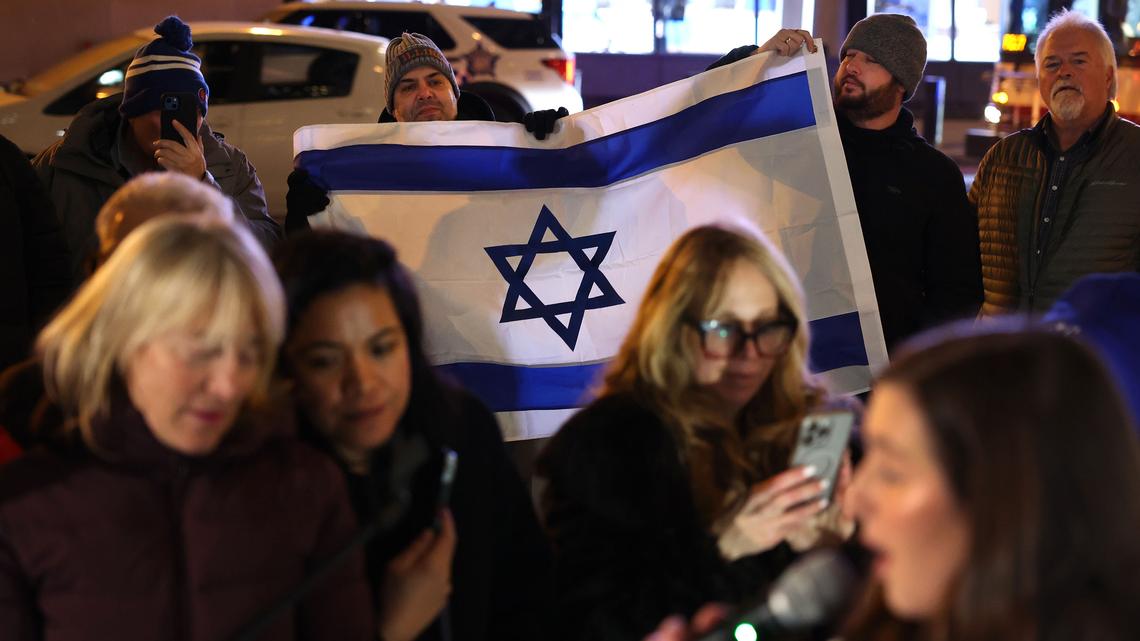 Two men hold an Israeli flag while attending a menorah lighting ceremony hosted by the Chabad Center for Jewish Life of the Loop and Gold Coast on Dec. 16, 2025, at Chicago’s Daley Plaza. (Chris Sweda/Chicago Tribune/TNS)