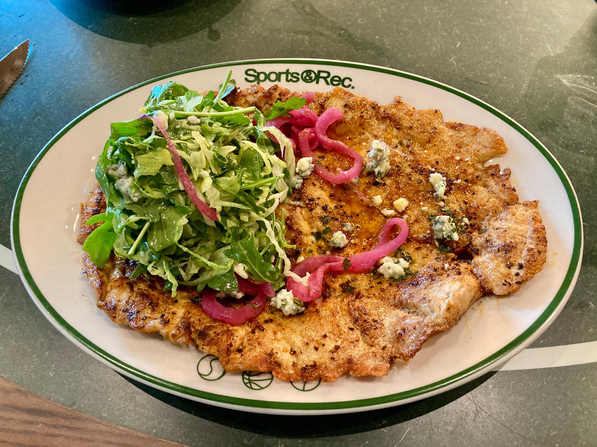 The Brown Butter Buffalo Chicken Paillard is an OMG dish at Sports & Rec. Pounded out to about a quarter inch thick and seared to perfection, it features arugula and iceberg lettuce, a blue cheese dressing with chunks of blue cheese, pickled celery and carrot chimichurri.
