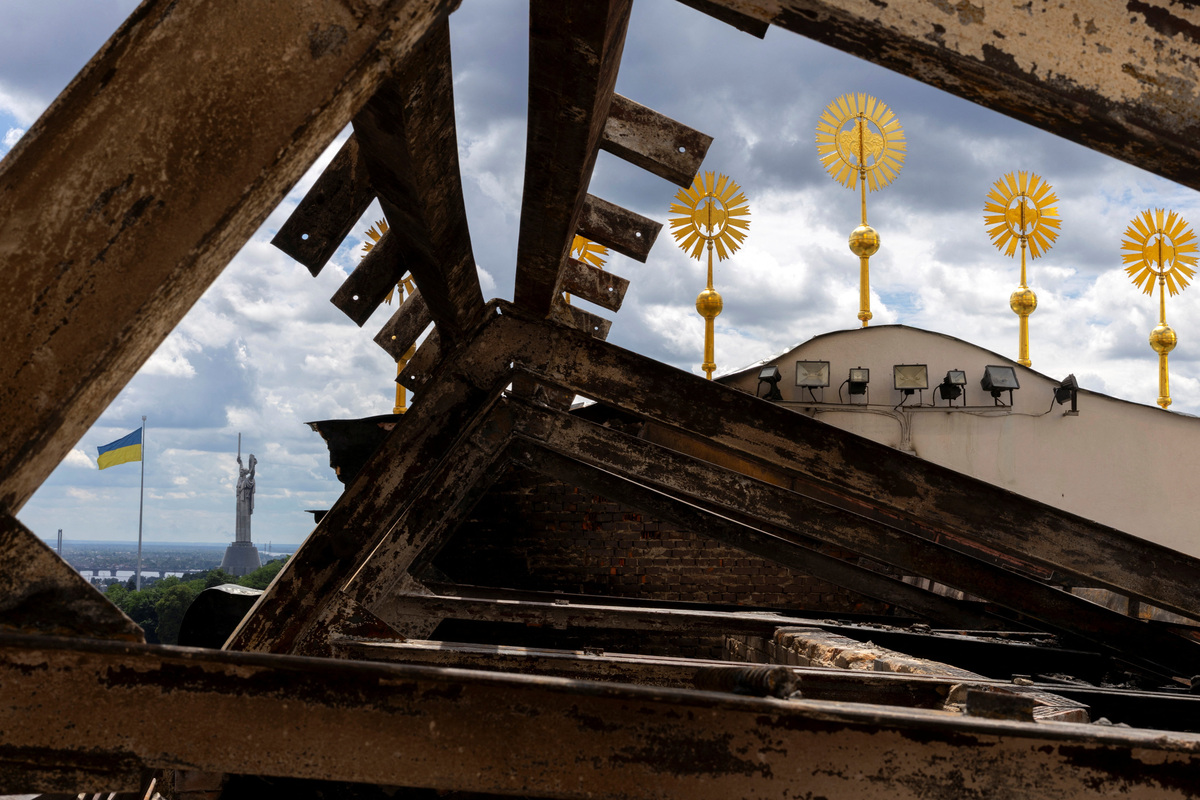 The Ukrainian flag and the Motherland Monument stand next to the burnt roof truss of the Dormition Cathedral of the Kyiv Pechersk Lavra, after it was hit during yesterday’s Russian missile and drone strikes, amid Russia's attack on Ukraine, in Kyiv, Ukraine June 16, 2026.  REUTERS/Thomas Peter