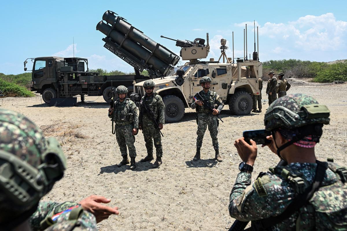 Philippine soldiers pose for a picture in front of the Japan Ground Self-Defense Force (JGSDF) Type 88 surface-to-ship missile launcher and the U.S. Marine Air Defense Integrated System (MADIS), during the Joint Task Force (JTF) Maritime Strike, part of Balikatan, the annual joint military exercises between the United States and the Philippines, at Culili Point Sand Dunes, Paoay, Ilocos Norte province, Philippines, May 6, 2026. REUTERS/Noel Celis