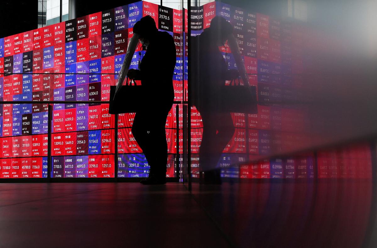 A man walks in front of an electronic screen displaying Japan's Nikkei stock prices quotation board inside a conference hall in Tokyo, Japan, April 27, 2026. REUTERS/Issei Kato/File Photo