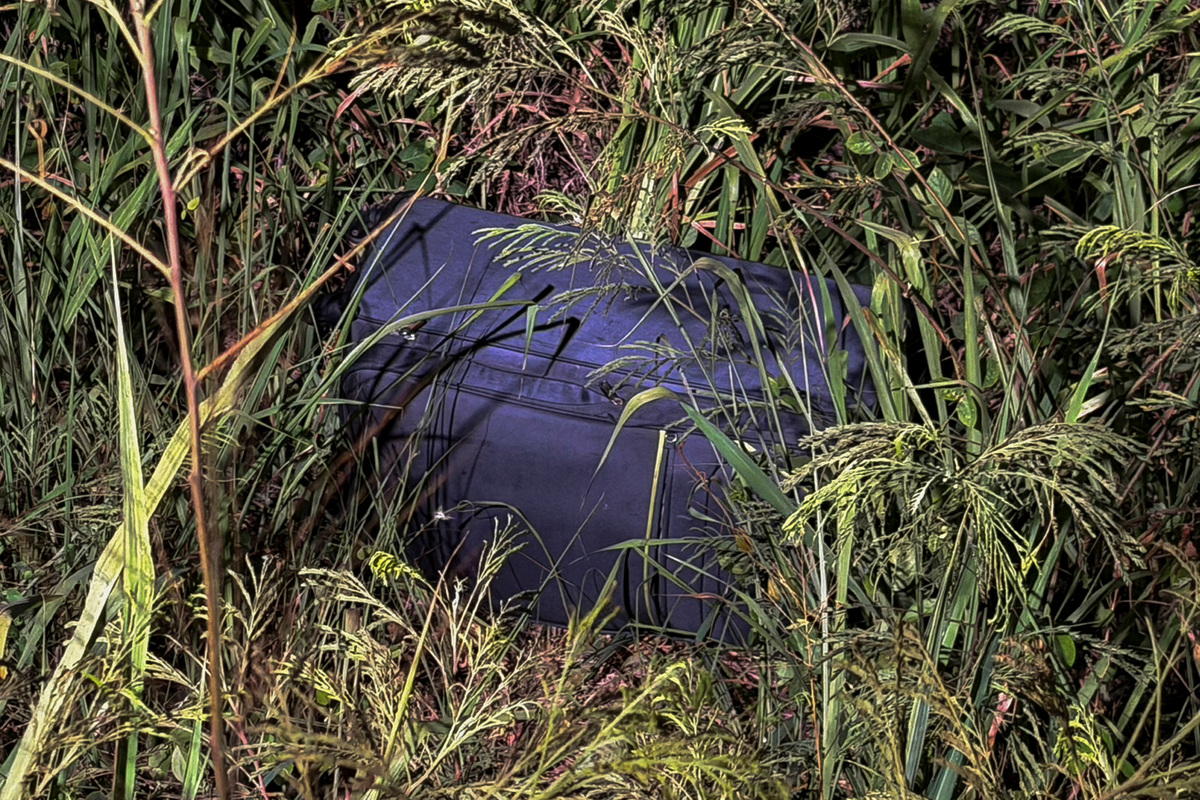 A suitcase in which police later found the body of a 17-year-old Thai girl lies in a grassy area near a railway track where it was discovered in Pattaya City, Thailand, June 27, 2026.  REUTERS/Teerasak Suttativong