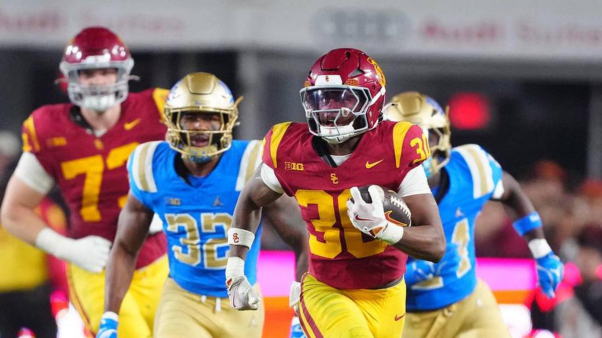  Nov 29, 2025; Los Angeles, California, USA; Southern California Trojans running back King Miller (30) carries the ball against UCLA Bruins linebacker Isaiah Chisom (32) in the first half at United Airlines Field at Los Angeles Memorial Coliseum. Mandatory Credit: Kirby Lee-Imagn Images | Kirby Lee-Imagn Images 