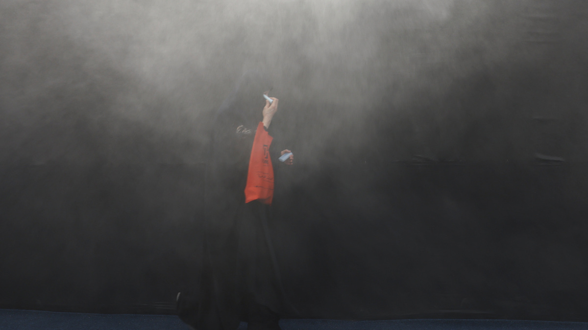 A Shi'ite Muslim woman walks through water mist sprayed to cool people from the heat ahead of Ashura, the holiest day on the Shi'ite Muslim calendar, in Karbala, Iraq June 25, 2026. REUTERS/Ahmed Saad