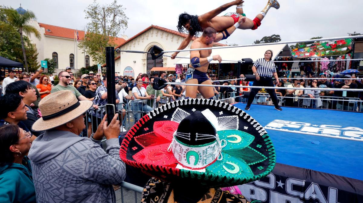 May 2, 2026_San Diego, CA_The Fiesta Cinco de Mayo celebration in Old Town- During a Lucha Libre match put on by San Marcos based So-Cal Pro Wrestling in a ring set up in the middle of San Diego Avenue wrestler Mathias, below, gets hit from above by flying Don Caliente (real name is Cecilio Lopez). (Charlie Neuman / For The San Diego Union-Tribune)