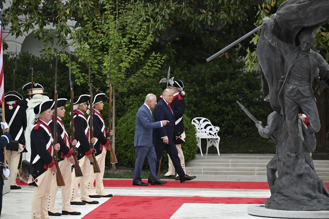 President Donald Trump, right, walks with King Charles III through the Rose Garden during an arrival ceremony at the White House in Washington, on Tuesday, April 28, 2026. The statue "Freedom's Charge" by sculptor Chas Fagan stands at right. (Kenny Holston/The New York Times)