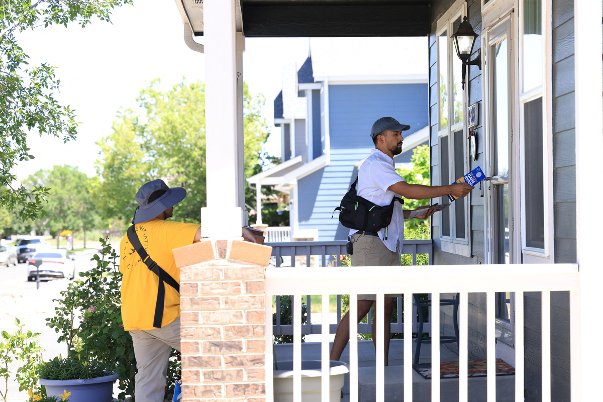 Angel Merlos of the right-leaning grassroots political organization, The LIBRE Initiative, hangs a door flyer on a home in support of U.S. Rep. Gabe Evans (R-CO) while canvassing a neighborhood in Brighton, Colorado, U.S., June 11, 2026. REUTERS/Kevin Mohatt