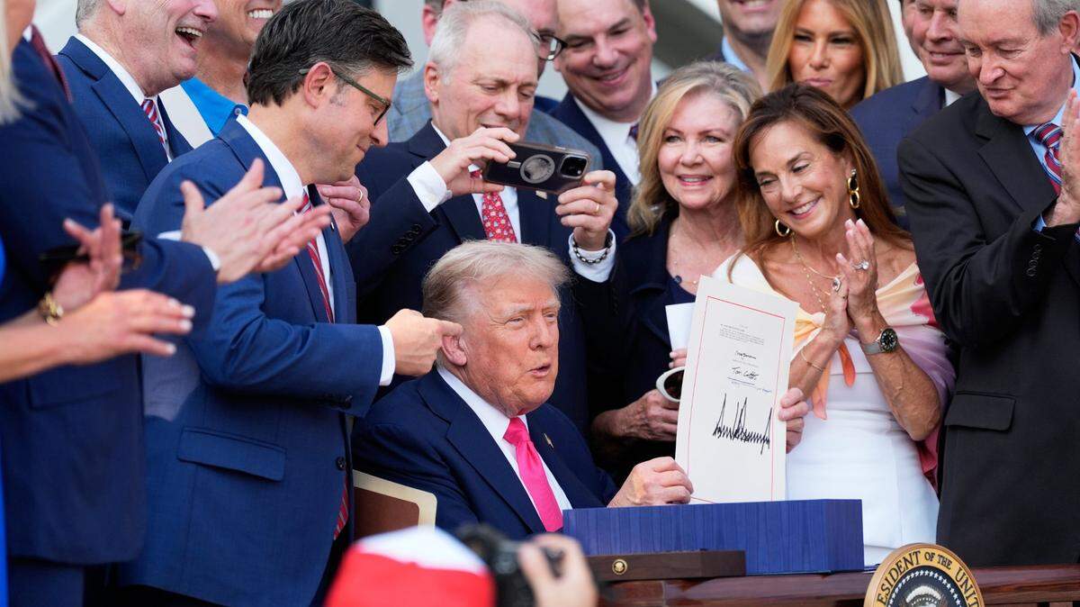 President Donald Trump holds up his signed signature bill of tax breaks and spending cuts at the White House in Washington on Friday, July 4, 2025.