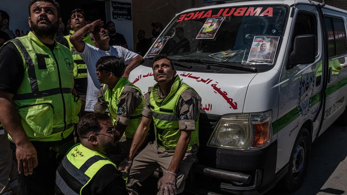 Civil defense workers look up towards the sound of an Israeli jet fighter flying above as mourners attend a funeral for photojournalist and paramedic Ahmad Hariri and two civil defense workers Ali Ghassani and Hussein Kassir in Tyre, Lebanon, Saturday, May 23, 2026. Dozens of Israeli airstrikes pounded Lebanon late Friday and early Saturday, killing and injuring several people, Lebanon's national news agency said, exposing the mounting strain on a truce between Israel and the Iran-backed Lebanese militant group Hezbollah. (Daniel Berehulak /The New York Times)