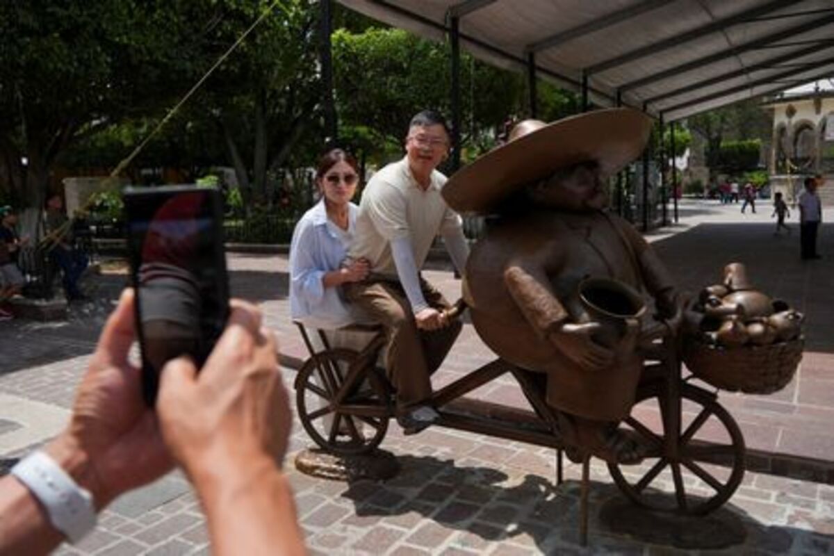 A South Korean couple pose on a bicycle sculpture by renowned local artist Rodo Padilla, as the bond between Korea and Mexico, one of the world’s more unusual geo-cultural connections, continues to grow, with Korean influence gaining a foothold despite distance, language barriers and a 15-hour time difference, in Tlaquepaque, Mexico, June 17, 2026. REUTERS/Ivan Arias