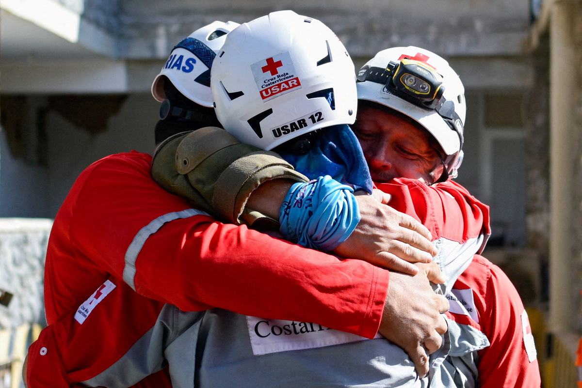 Rescue workers hug each other after pulling out survivor Hernan Alberto Gil, who was trapped for over a week following June 24 earthquakes, from a collapsed mall in La Guaira, Venezuela, July 2, 2026. REUTERS/Maxwell Briceno