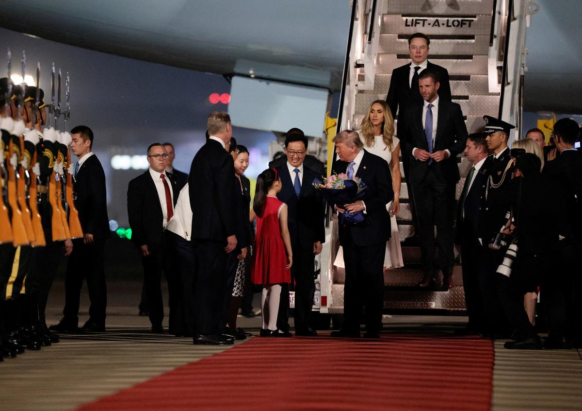 U.S. President Donald Trump receives flowers, next to Elon Musk, Eric Trump and his wife Lara, during an arrival ceremony at Beijing Capital International Airport, in Beijing, China, May 13, 2026. REUTERS/Evan Vucci