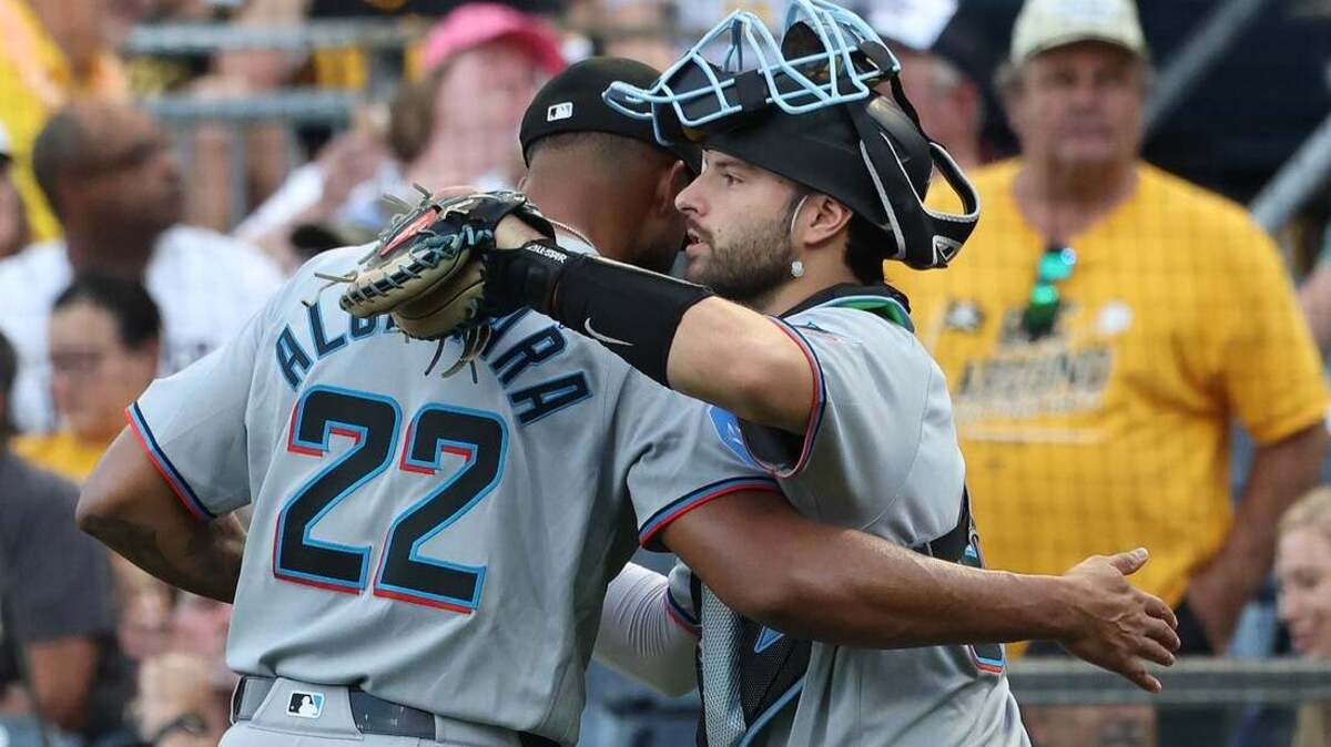 El lanzador abridor de los Miami Marlins, Sandy Alcántara (22), celebra con el receptor Joe Mack (derecha) después de ponchar al jardinero izquierdo de los Pittsburgh Pirates, Tyler Callihan (no aparece en la imagen), para registrar el ponche número 1000 de su carrera en la MLB durante la cuarta entrada en el PNC Park.
