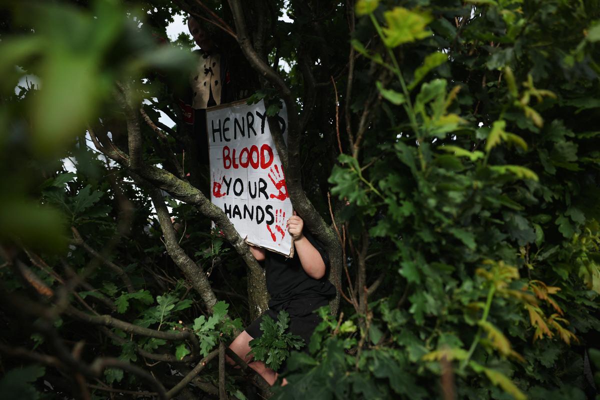 A demonstrator is surrounded by branches while holding a placard outside Southampton Central Police Station following the conviction of Vikrum Digwa for the murder of student Henry Nowak, in Southampton, Britain, June 2, 2026. REUTERS/Isabel Infantes