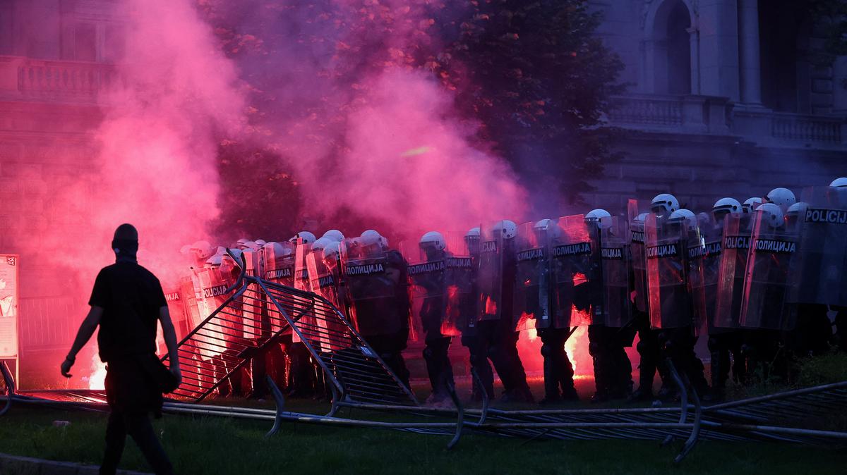 A demonstrator walks near riot police, as a flare emits smoke, during a student-led protest demanding snap parliamentary elections, as Serbia's anti-corruption movement enters a new phase, following the Novi Sad railway station canopy collapse that killed 16 people in 2024, in Belgrade, Serbia, May 23, 2026. REUTERS/Zorana Jevtic