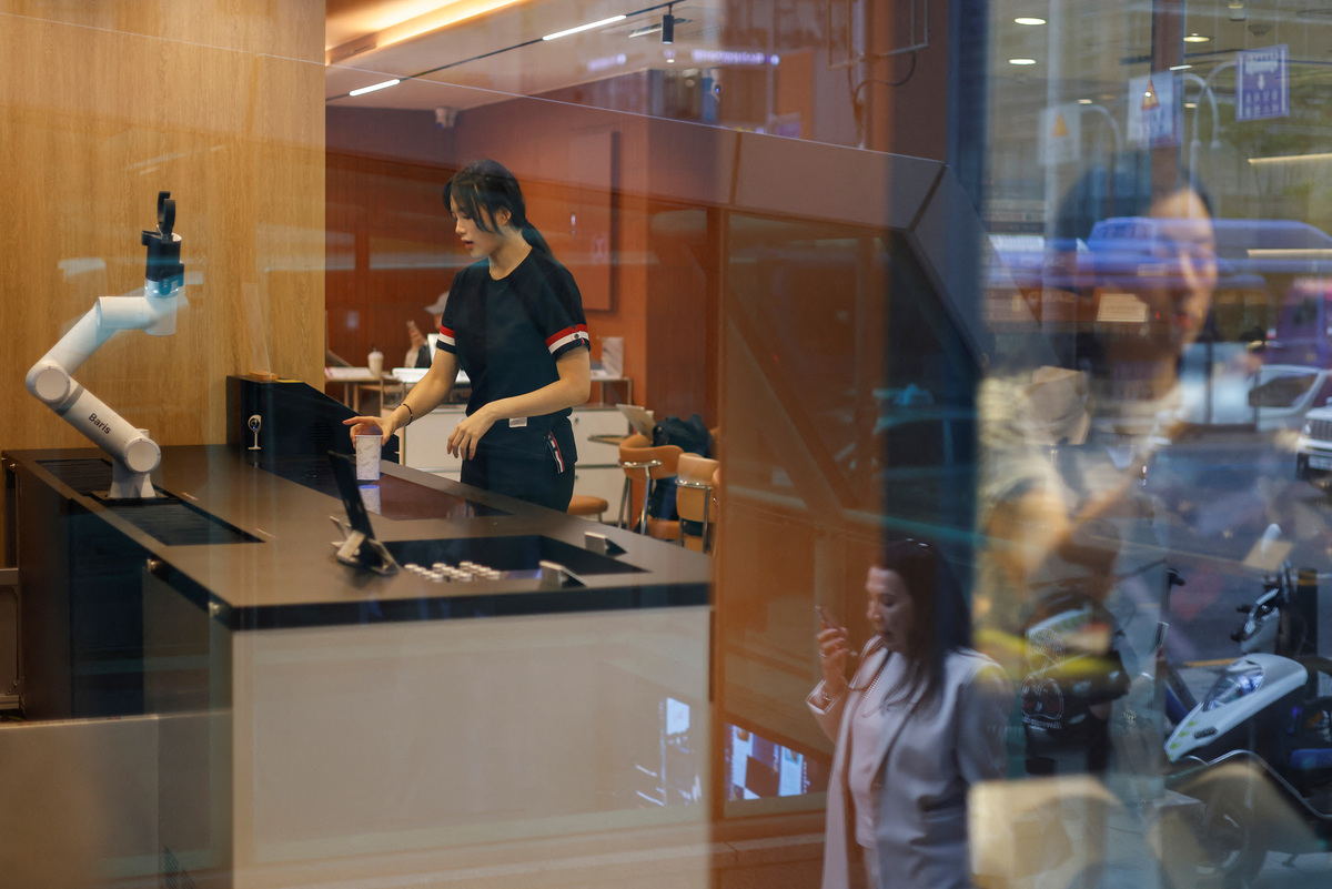A customer gets coffee prepared by a robot arm at an unmanned cafe in Seoul, South Korea, June 19, 2026. REUTERS/Kim Soo-hyeon