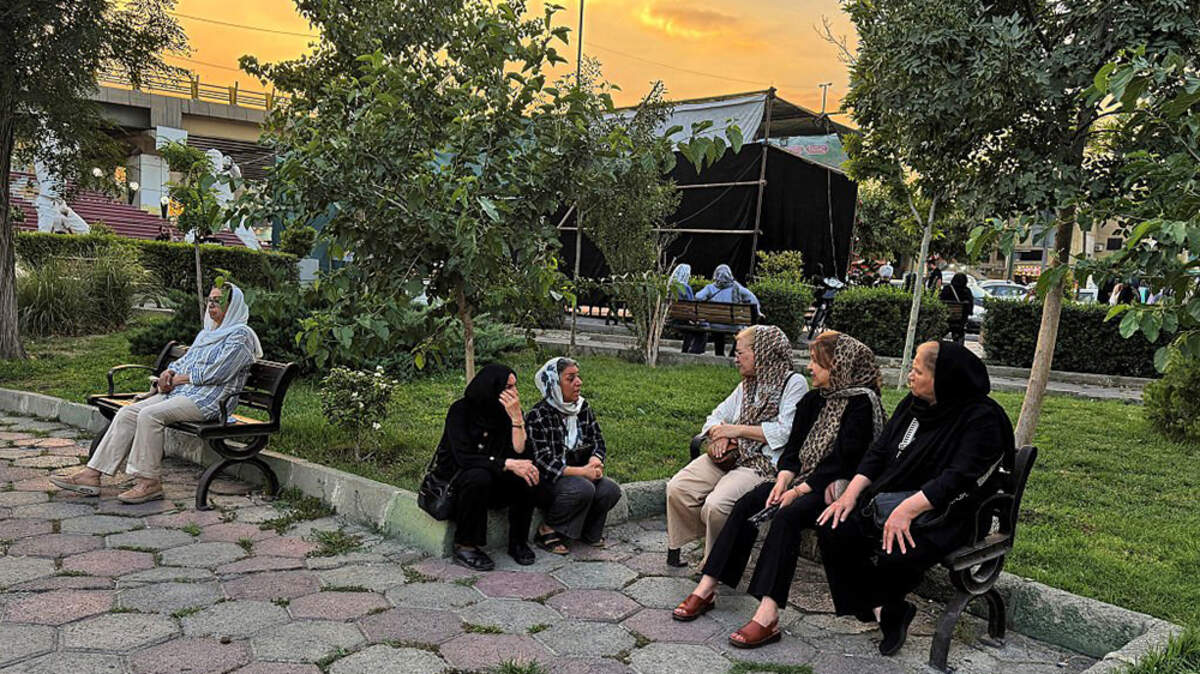 Iranians chat in a park in Tehran on Monday. The United States temporarily suspended sanctions on Iranian oil after Vice President JD Vance said Iran would allow U.N. nuclear inspectors to return to the country, following talks in Switzerland.