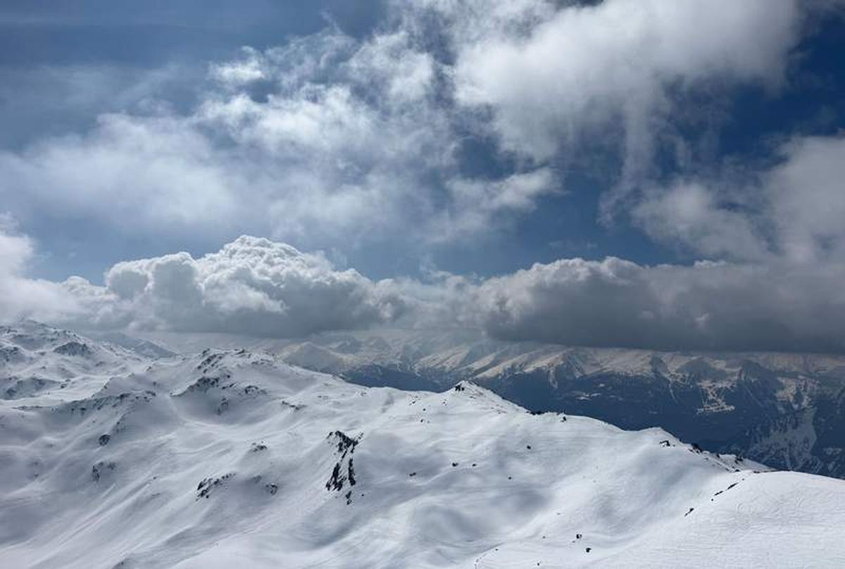  The view from Restaurant Le 2800 at Les Menuires stops you mid-bite – snow-covered peaks rolling toward the horizon under a sky that can't decide what it wants to do. Photo credit: Liana Moore 