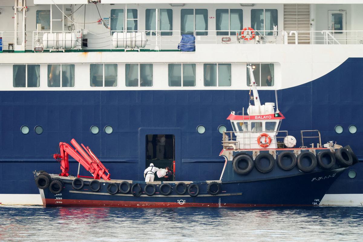 A person wearing personal protective equipment (PPE) on a boat transfers a package to the cruise ship MV Hondius at the port of Granadilla de Abona after being affected by a hantavirus outbreak in Tenerife, Spain, May 10, 2026. REUTERS/Hannah McKay