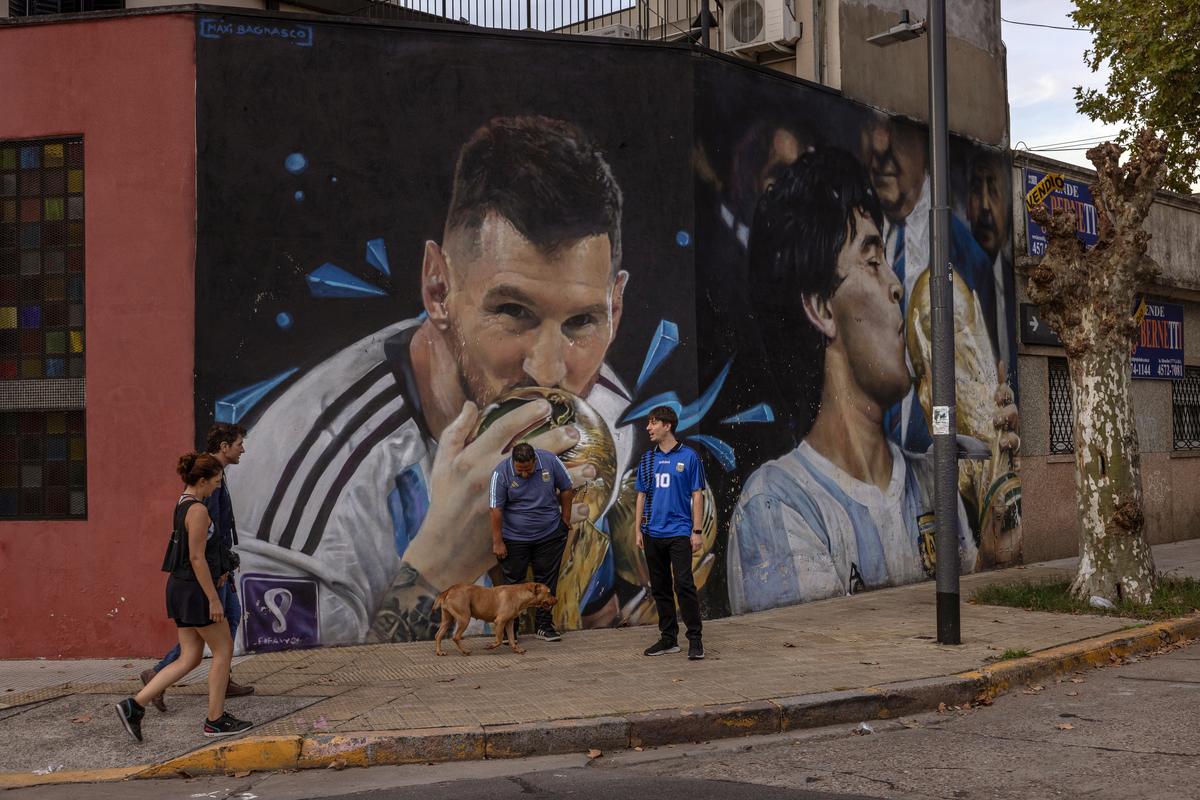 Soccer fans Jose Serio, center, and Rodrigo Diez, right, in front of one of the many murals depicting Lionel Messi and Diego Maradona in Buenos Aires, Aregtnina, on April 14, 2026. Dynamic ticket pricing has made this year's World Cup tournament the most expensive in history, pushing Argentine fans to extremes. (Sarah Pabst/The New York Times)