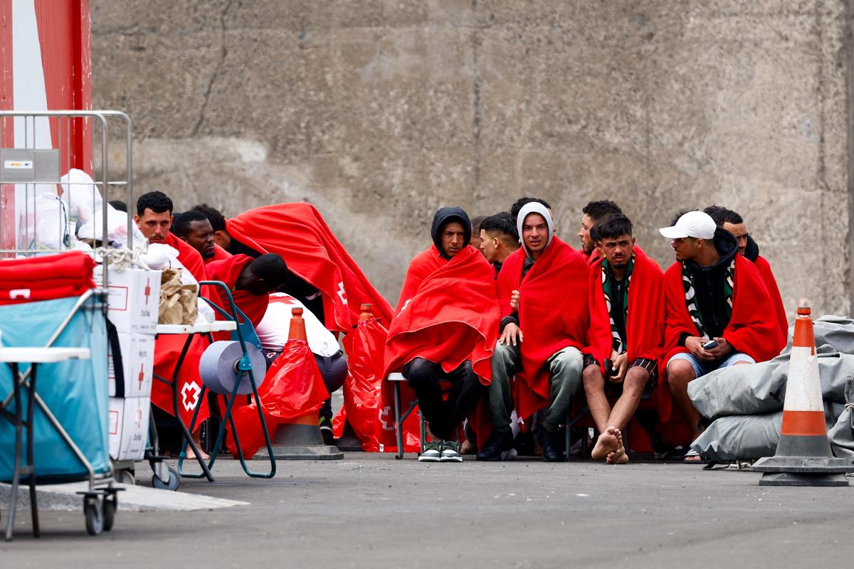 FILE PHOTO: Migrants wait to be assisted by the Red Cross after disembarking from a Spanish coast guard vessel at the port of Arguineguin, on the island of Gran Canaria, Spain, April 4, 2026. REUTERS/Borja Suarez/File Photo