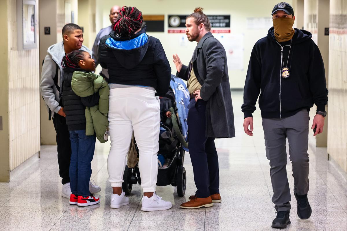  A federal agent walks past a family in the halls of immigration court at New York’s Jacob K. Javits Federal Building on March 5, 2026. 