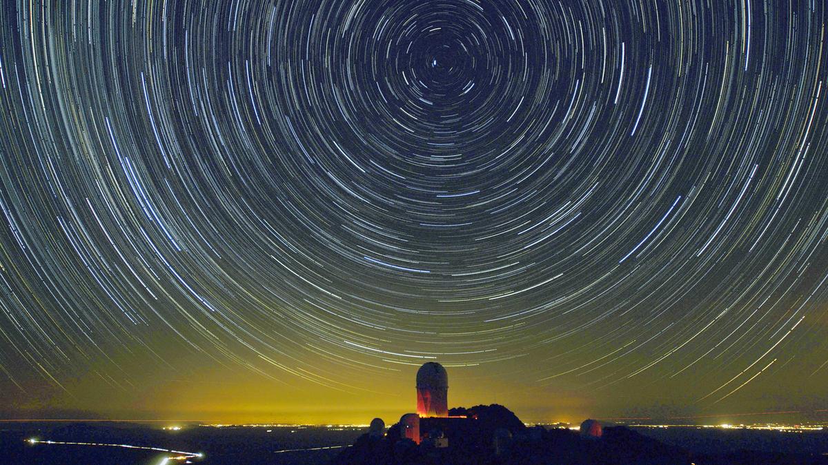 Stars appear to rotate around Polaris, the north star (C, top), in this time exposure, Jan. 26, 2006, above a view of the 4-meter telescope dome at Kitt Peak National Observatory near Tucson, Arizona. The image is composed of 114 30-second exposures of the night sky combined to make the equivalent of a nearly one hour exposure in which the earth's rotation causes the stars to appear to move across the night sky. The orange glow on the horizon is from the city of Phoenix, 100 miles (160 Km) away. (Stan Honda/AFP/Getty Images/TNS)