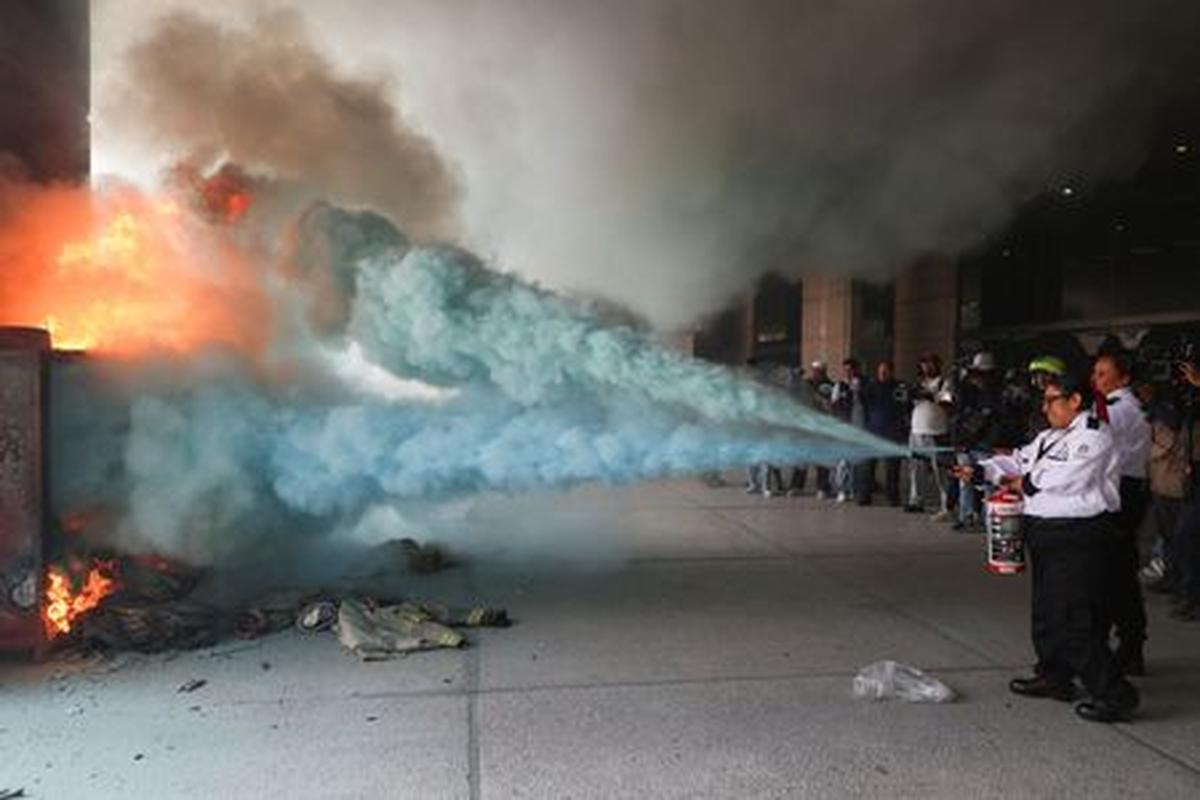 Private security guards work to extinguish a fire at the Secretariat of Public Education (SEP) after it was vandalized by dissident teachers from Mexico's National Coordination of Education Workers (CNTE) during a protest to demand better wages and pensions, under the slogan "If there's no solution, the ball won't roll," ahead of the 2026 FIFA World Cup, in Mexico City, Mexico, June 3, 2026. REUTERS/Luis Cortes