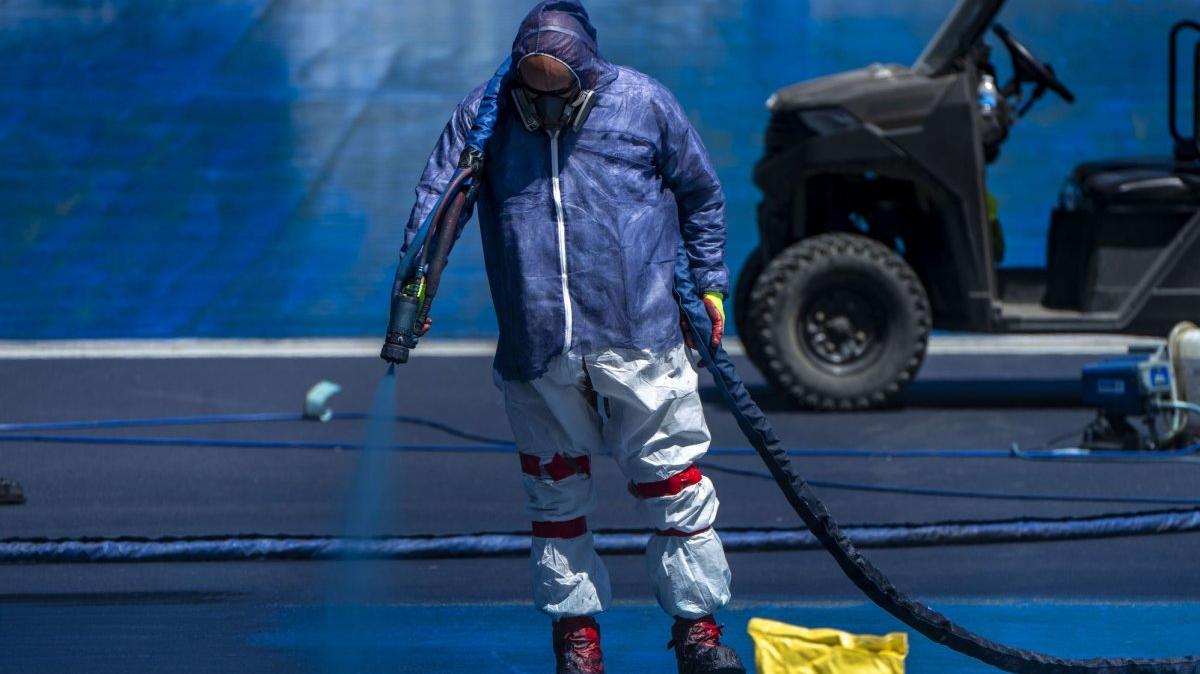 Workers in gas masks and protective gear paint the reflecting pool blue during its paint renovation in Washington, D.C., on Friday. Photo by Bonnie Cash/UPI