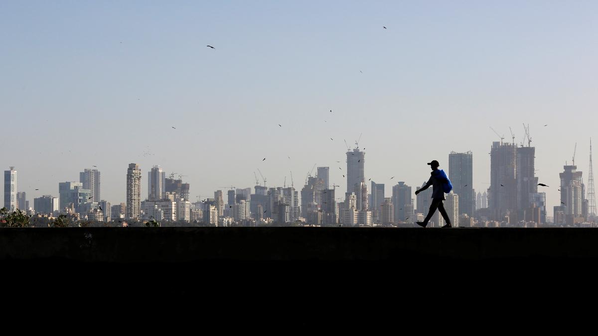 FILE PHOTO: A man walks along a wall overlooking the central Mumbai's financial district skyline, India, March 9, 2017. REUTERS/Danish Siddiqui/File Photo
