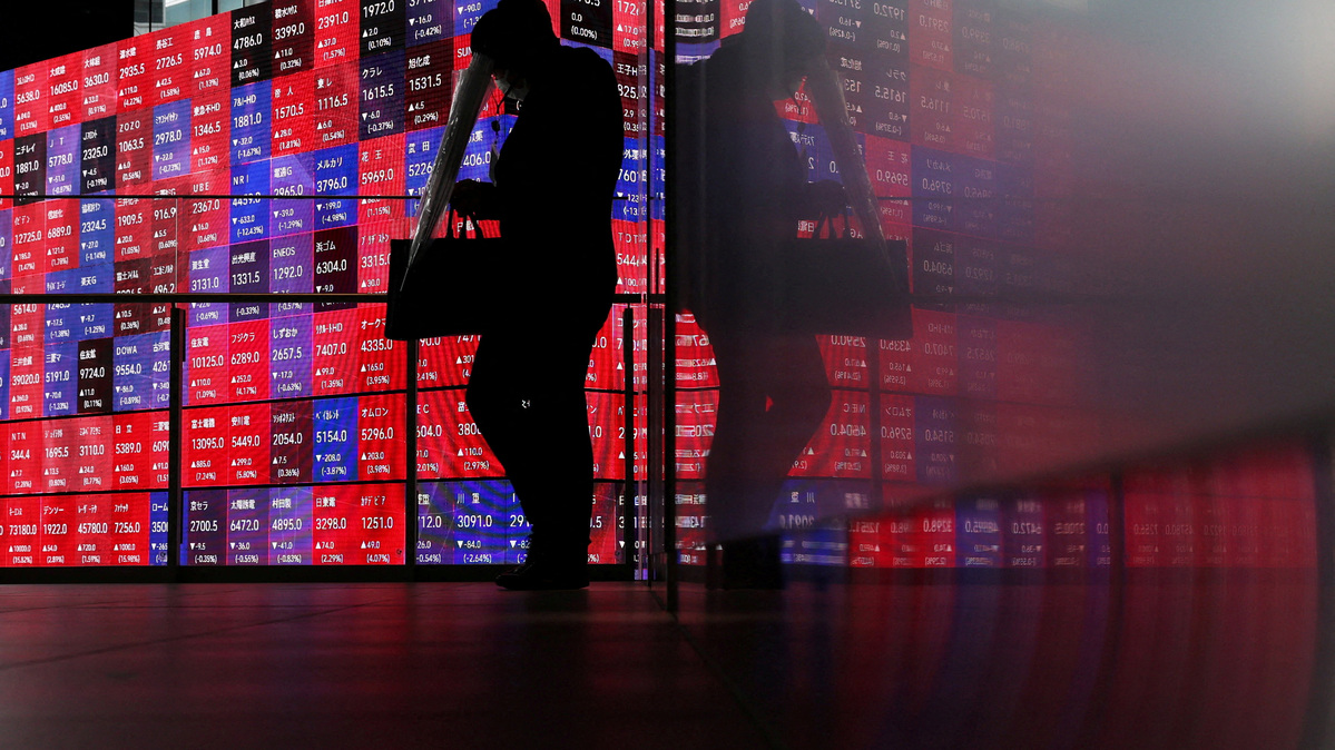 FILE PHOTO: A man walks in front of an electronic screen displaying Japan's Nikkei stock prices quotation board inside a conference hall in Tokyo, Japan, April 27, 2026. REUTERS/Issei Kato/File Photo