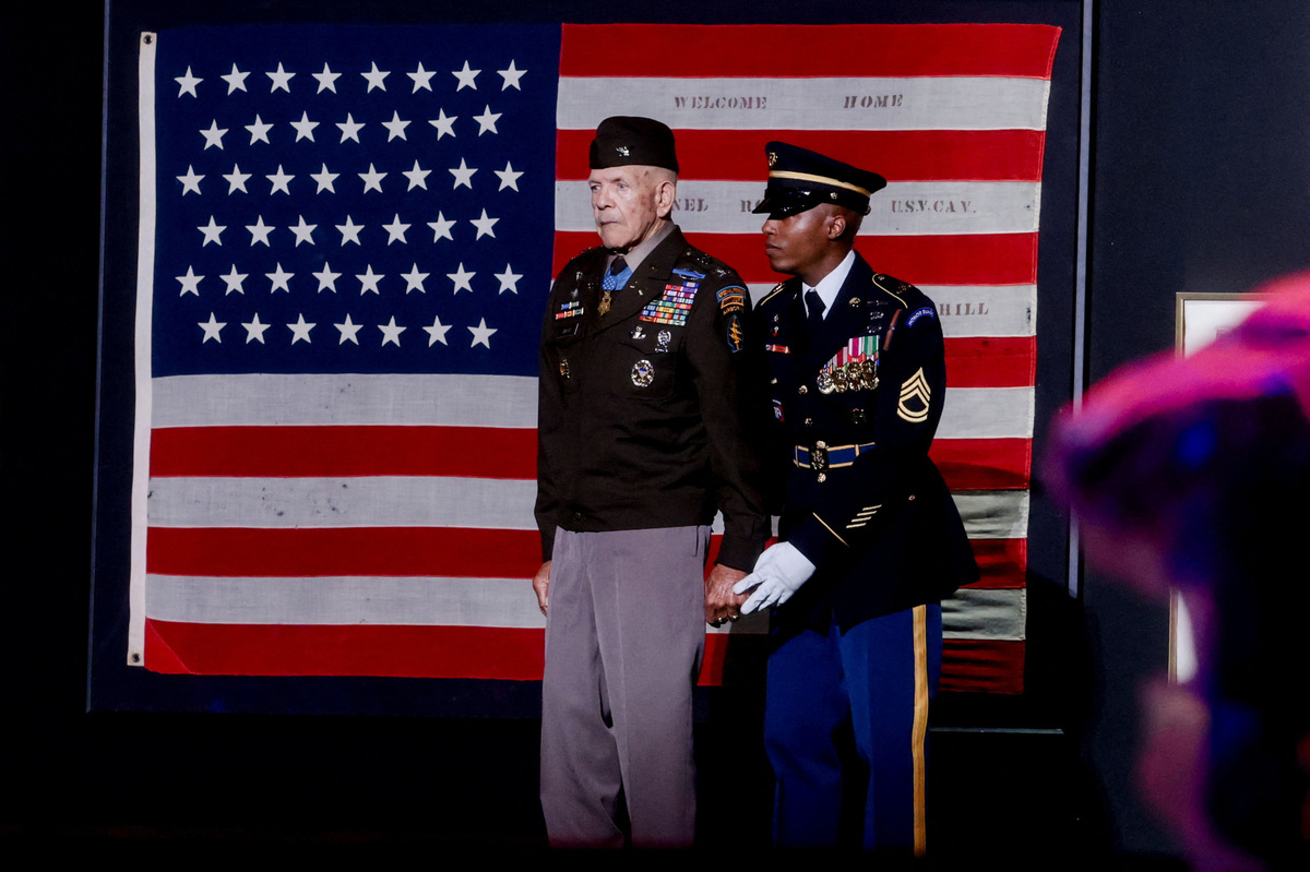 Retired U.S. Army Colonel and Medal of Honor recipient Paris D. Davis walks past Revolutionary-era "First American" flags while being accompanied to the stage as U.S. President Donald Trump (not pictured) speaks at a Fourth of July rally, marking the 250th anniversary of U.S. independence, on the National Mall in Washington, D.C., U.S., July 4, 2026.  REUTERS/Jonathan Ernst