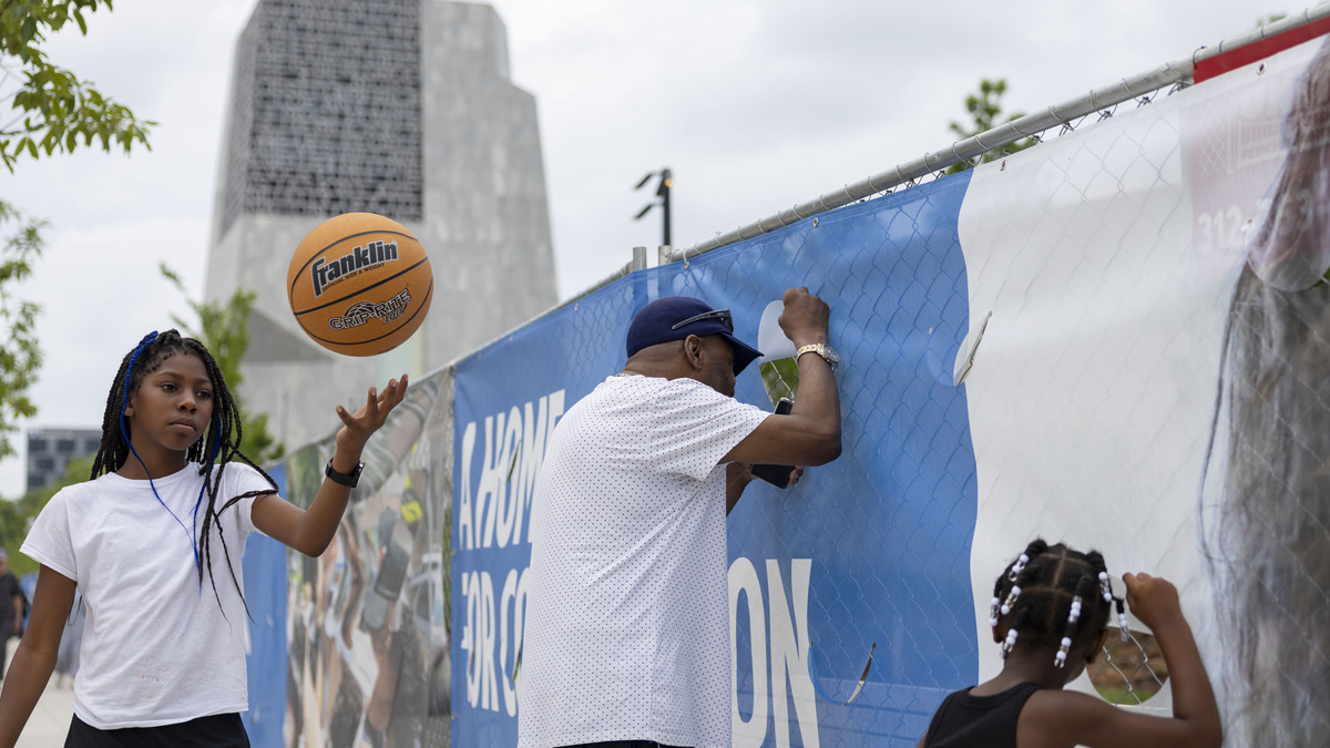 Alfred Coleman brings his granddaughters, Peyton, 12, and Alyah, 4, to peek through the fence at the Obama Presidential Center on June 8, 2026, in Chicago’s Jackson Park. (Brian Cassella/Chicago Tribune)