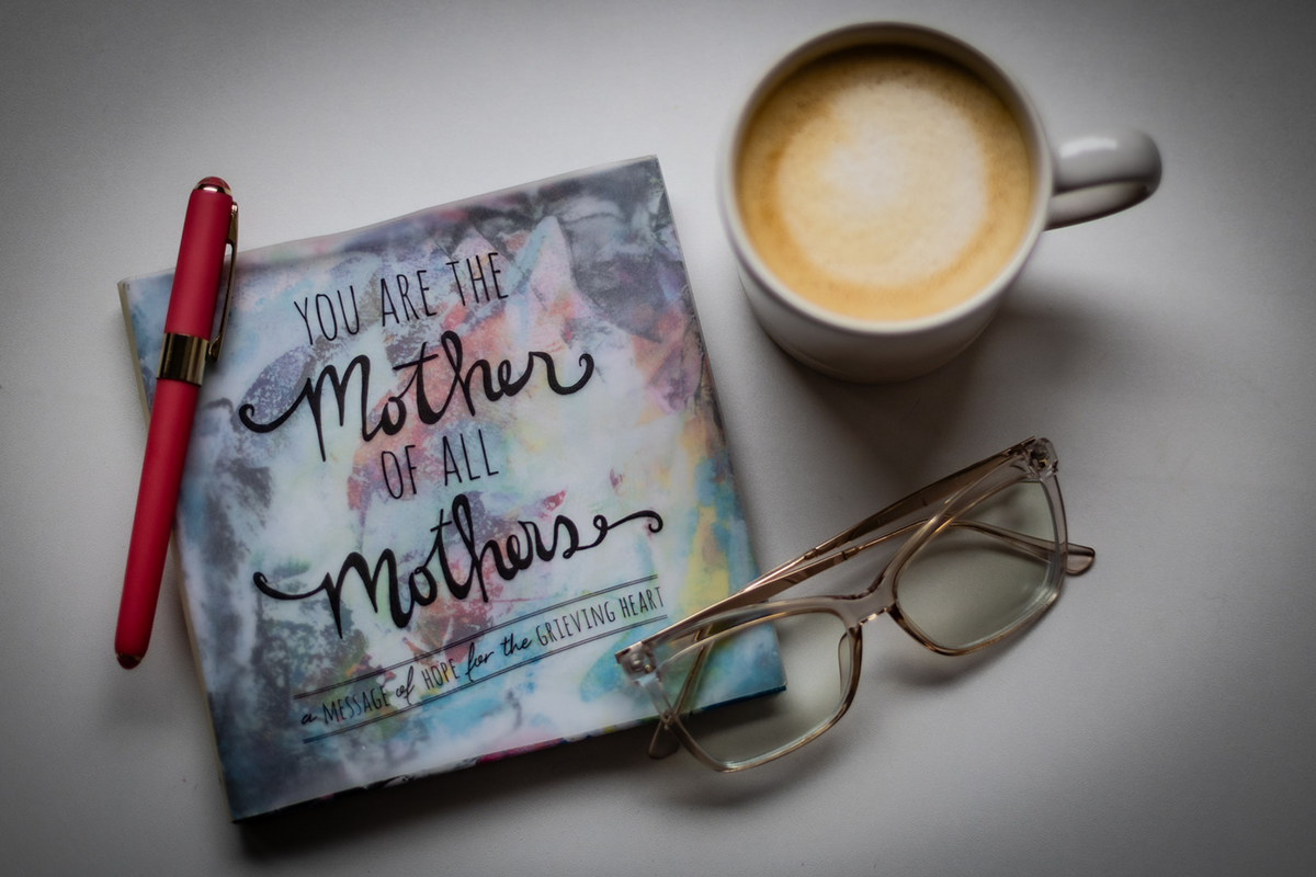  A flatlay image of a notebook, pen, a pair of glasses and a cup of coffee. 