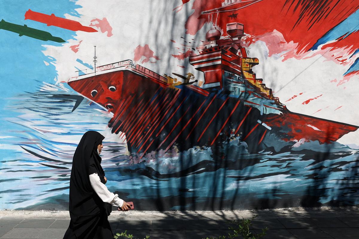 A woman walks next to a mural on a street in Tehran, Iran.  Majid Asgaripour/WANA