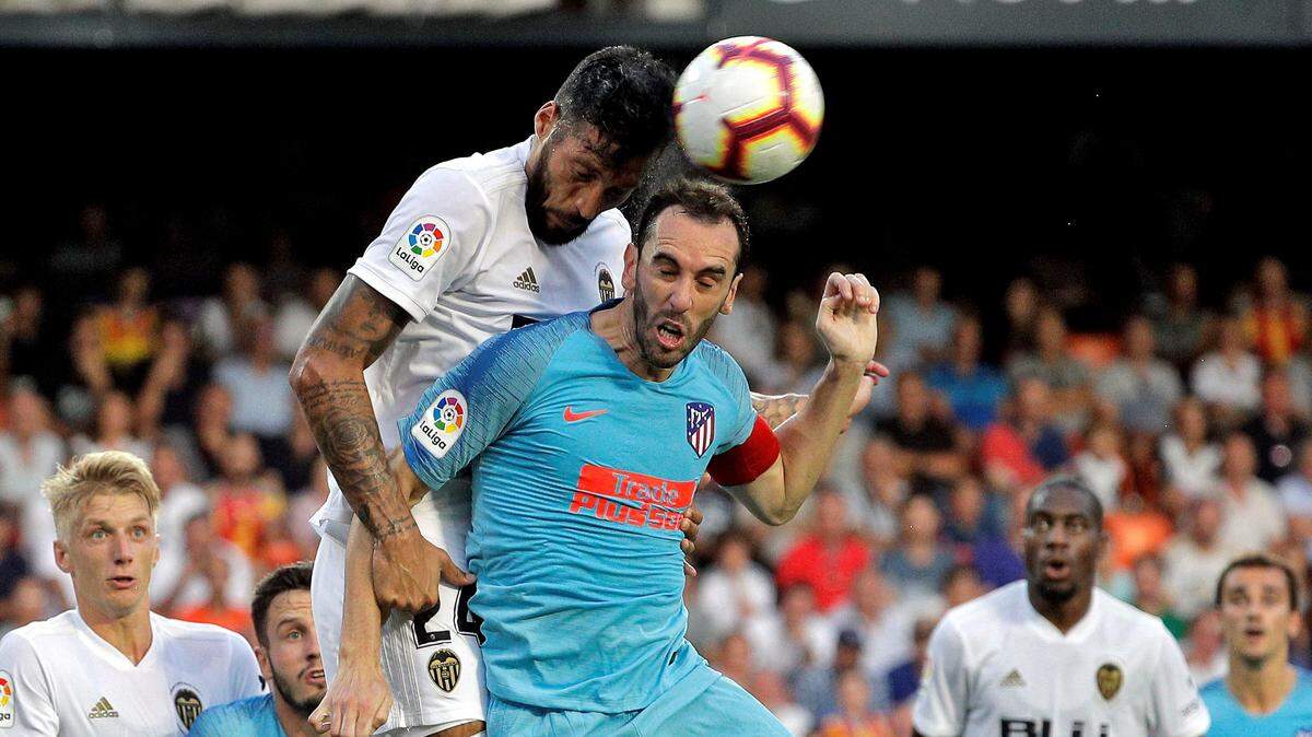 El defensa uruguayo del Atlético de Madrid, Diego Godín (der.), cabecea el balón ante el jugador argentino del Valencia CF, Ezequiel Garay, durante el partido correspondiente a la primera jornada de liga española, celebrado el 20 de agosto de 2018 en el estadio de Mestalla, en Valencia.
