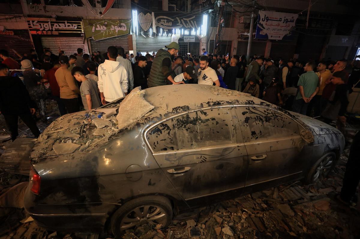 Palestinians stand by a damaged car, at the site of an Israeli airstrike on a residential building in Gaza City, May 26, 2026. REUTERS/Dawoud Abu Alkas