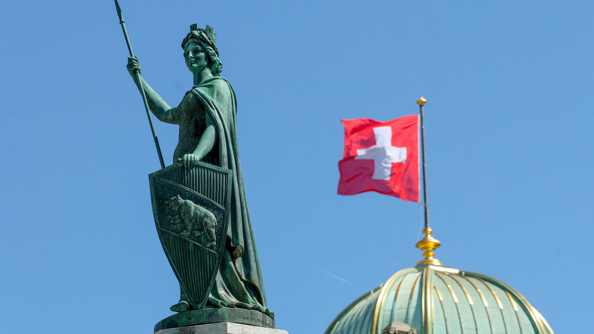 The Helvetia statue in front of a Swiss flag on the Swiss Parliament building (Bundeshaus) ahead of a press conference on Swiss banks' capital requirements in Bern, Switzerland, April 22, 2026. REUTERS/Denis Balibouse