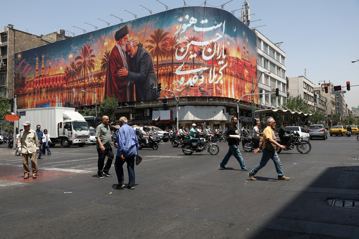 People move past a billboard with an image which depicts Iran's late Supreme Leader Ayatollah Ali Khamenei embracing late senior Iranian military commander General Qassem Soleimani, in Tehran, Iran, June 28, 2026. Majid Asgaripour/WANA (West Asia News Agency) via REUTERS