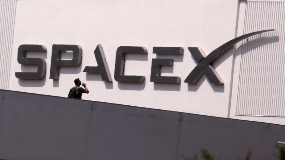 HAWTHORNE, CA - JULY 17, 2024 - An employee walks across the bridge from parking to SpaceX in Hawthorne on July 17, 2024. Elon Musk said Tuesday on X that he is moving the headquarters of both SpaceX and the social media platform formerly known as Twitter to Texas - citing several criticisms he has of California. (Genaro Molina/Los Angeles Times)