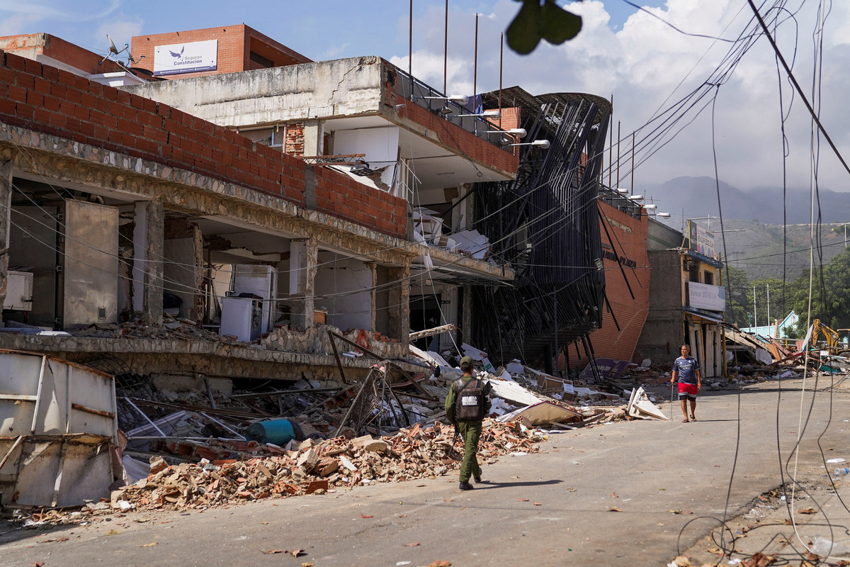 A member of the Bolivarian National Armed Forces walks along damaged buildings one week after earthquakes struck the country, in La Guaira, Venezuela, July 1, 2026. REUTERS/Marian Carrasquero