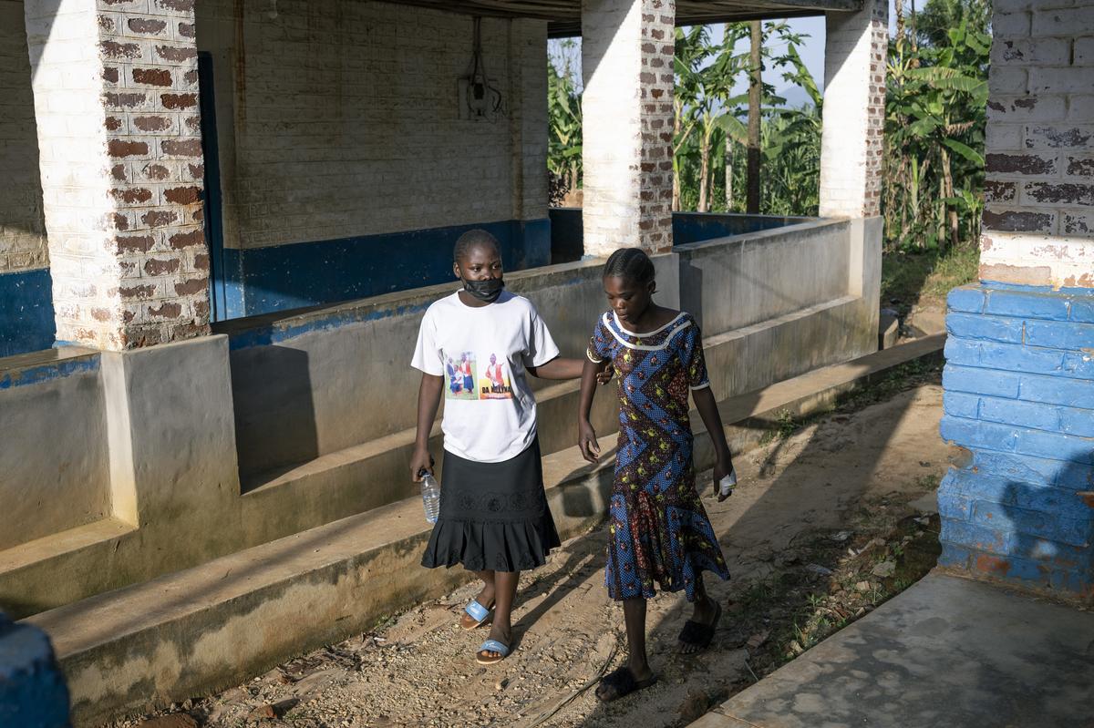 A woman steadies her sick sister as they make their way to a hospital's Ebola ward in the mining town of Mongbwalu, Democratic Republic of Congo, May 24, 2026. In a remote gold mining town at the epicenter of the Ebola outbreak, medical workers struggle to beat back a surge of deaths and infections. (Arlette Bashizi/The New York Times)