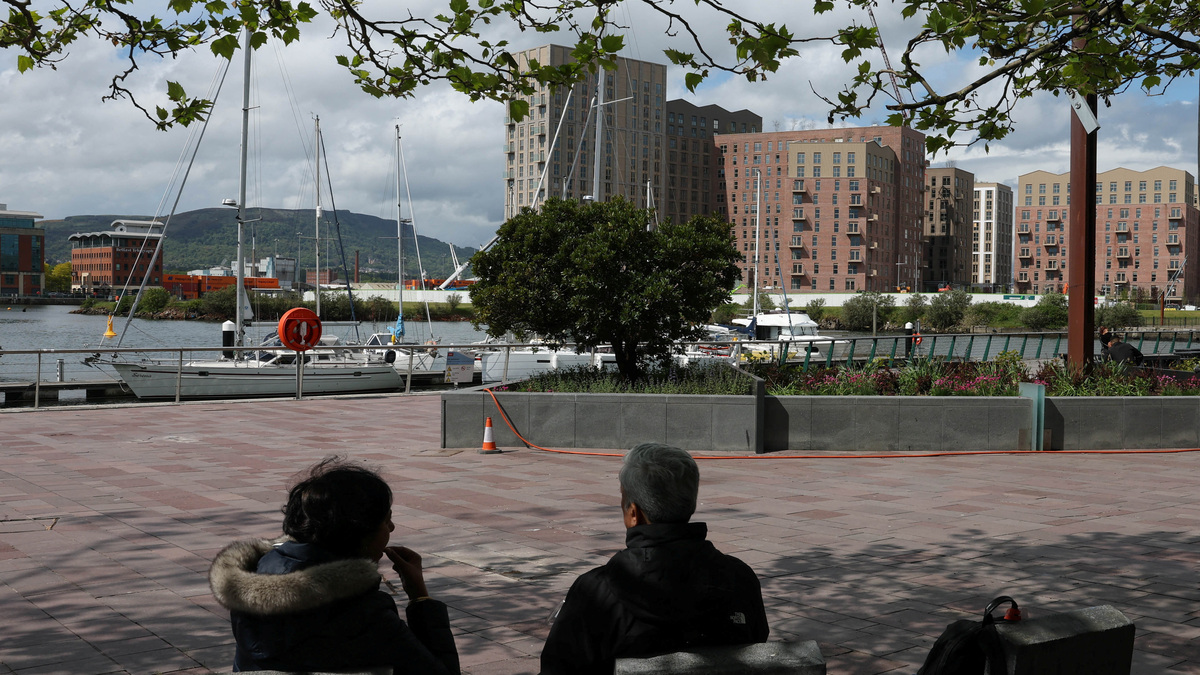 People relax by the waterside in the Titanic Quarter area in Belfast, Northern Ireland, May 19, 2026. REUTERS/Toby Melville/File Photo