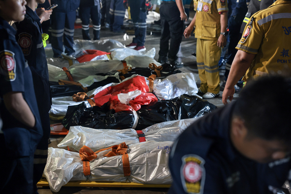 Members of emergency personnel work next to covered bodies at the site of a deadly fire at a pub in Bangkok, Thailand, July 13, 2026. REUTERS/Chalinee Thirasupa