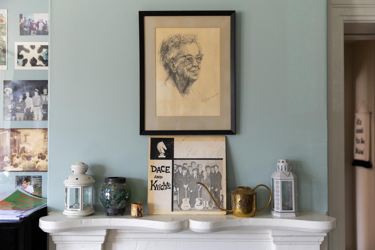 A portrait of Dacie Moses hangs over an album that the Singing Knights, a campus a cappella group, named for her, at the Dacie Moses House, Carleton College's cookie house in Northfield, Minn., March 31, 2026. For decades, Carleton College has kept a place where students and others can come, bake and share. (Liam James Doyle/The New York Times)