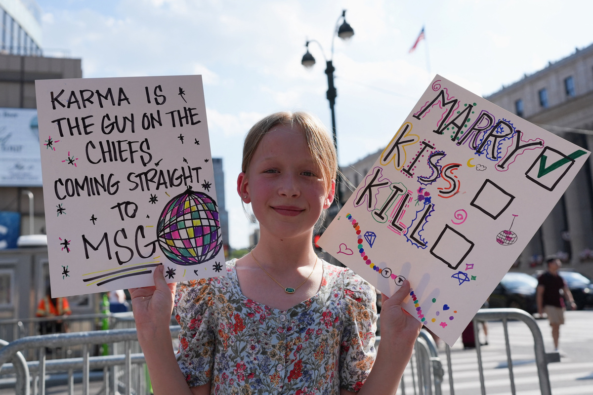 A child holds placards near Madison Square Garden, the venue for the reported wedding celebrations of singer Taylor Swift and National Football League (NFL) player Travis Kelce, in New York, U.S., July 3, 2026.  REUTERS/Christian Monterrosa