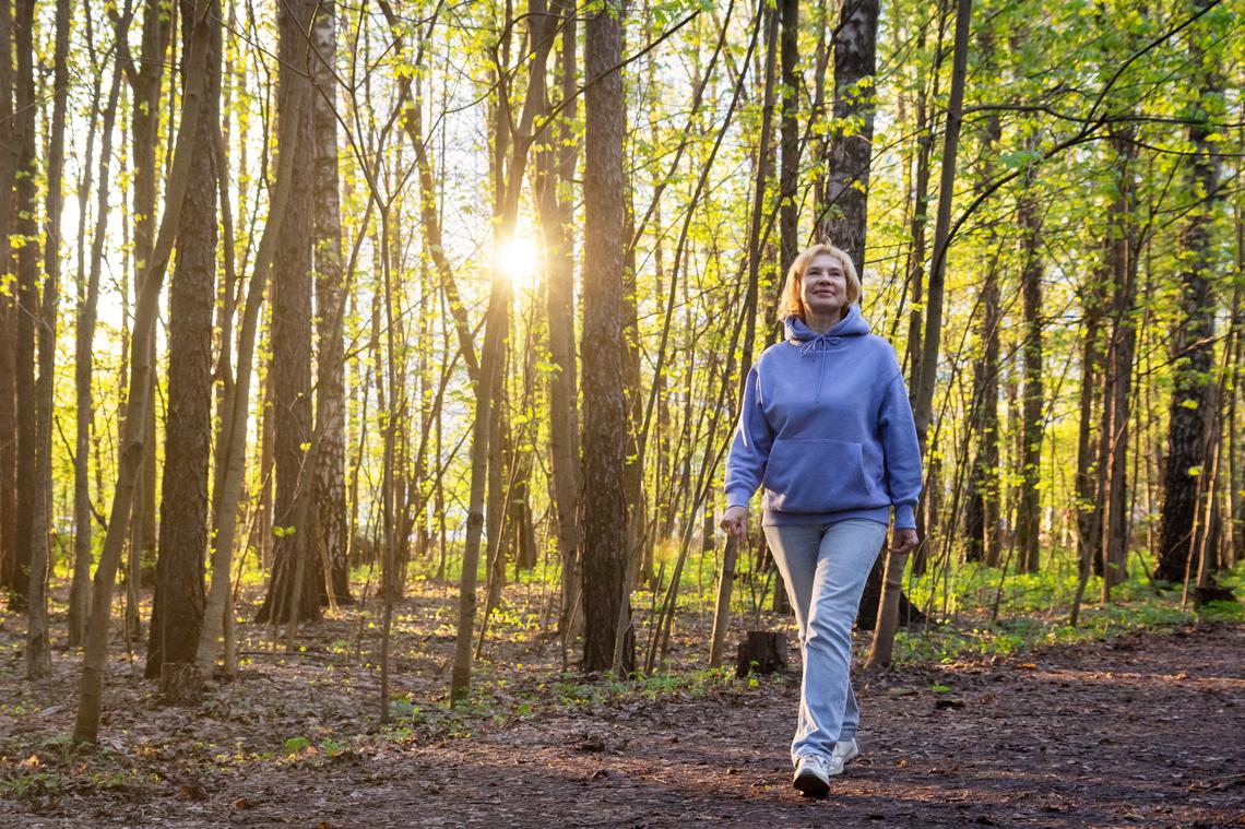 Happy woman walking in sunlit park at sunset in spring.